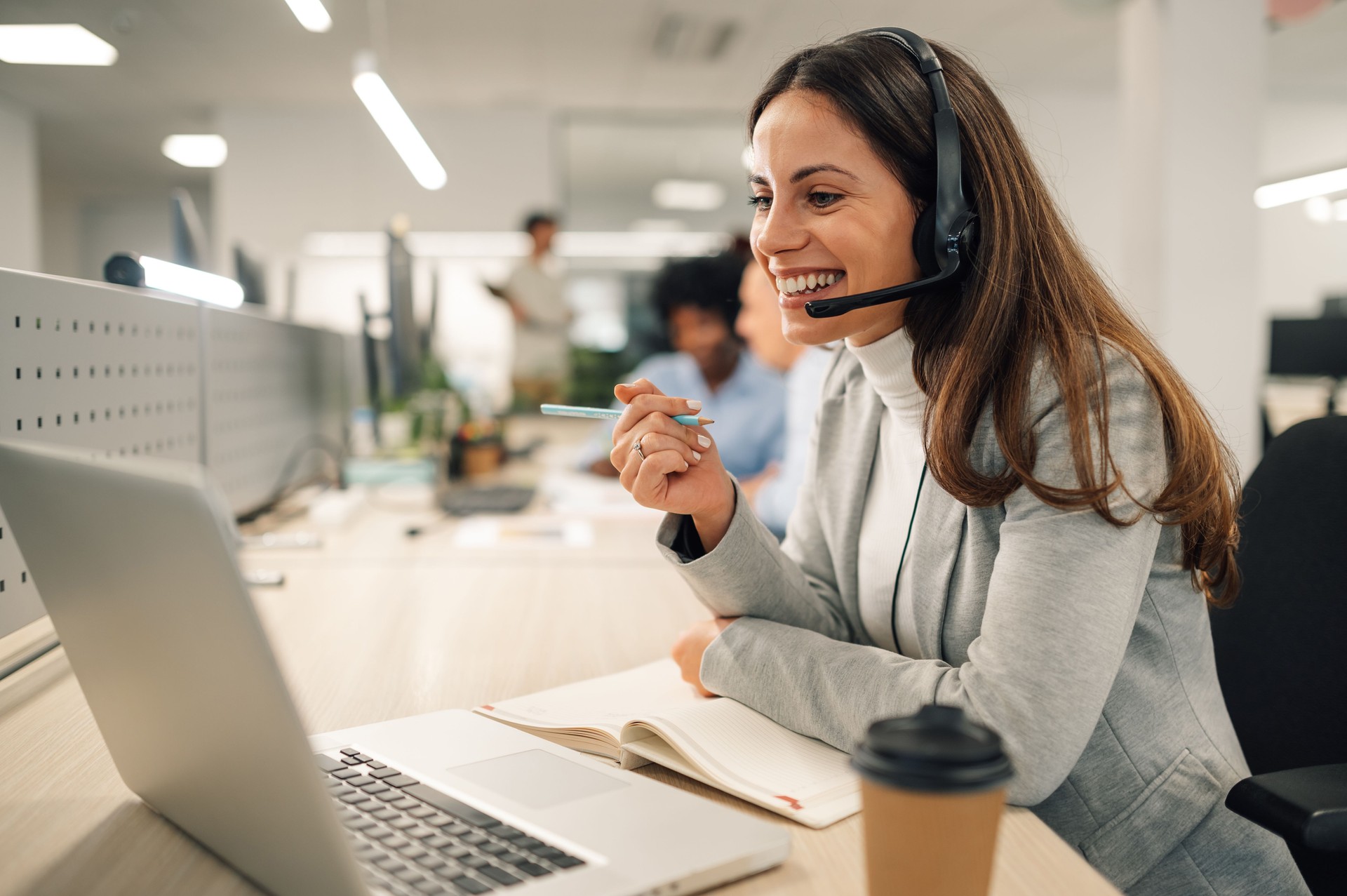 Caucasian business woman with headset working on a laptop in a call center Caucasian business woman with headset working on a laptop in a call center